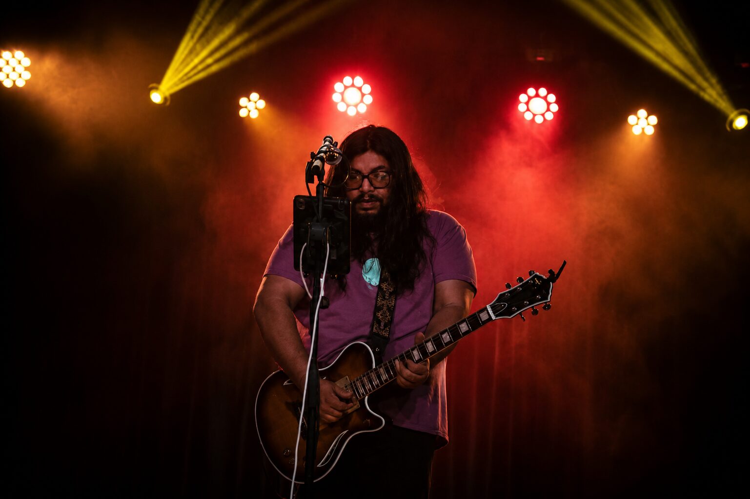 Jesse James Armijo on stage under colorful dramatic stage lights